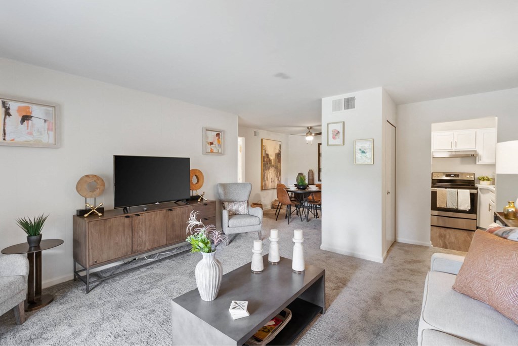 A modern living room with a grey carpet and a wooden entertainment center at The Waverly on the Lake - Belleville, MI Apartment , Michigan, 95050