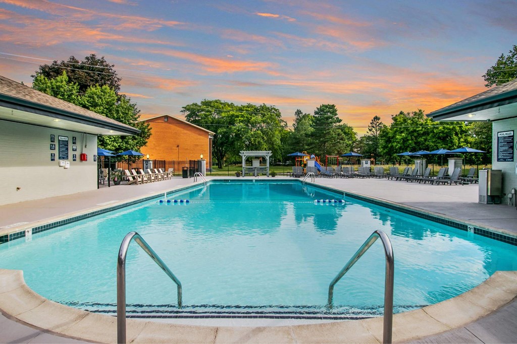 A large swimming pool with a metal ladder in the foreground at The Waverly on the Lake - Belleville, MI Apartment , Belleville, MI