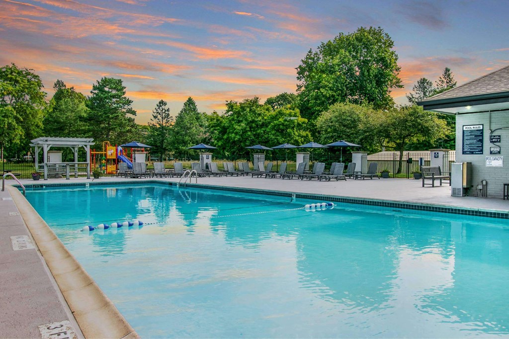 A large swimming pool with a sunset in the background at The Waverly on the Lake - Belleville, MI Apartment , Belleville, Michigan