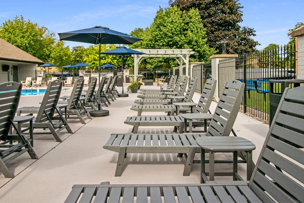 A poolside area with sun loungers and umbrellas at The Waverly on the Lake - Belleville, MI Apartment , Michigan