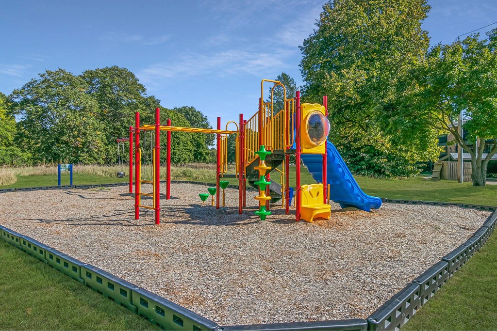 A playground with a yellow slide and a green slide at The Waverly on the Lake - Belleville, MI Apartment , Michigan, 95050