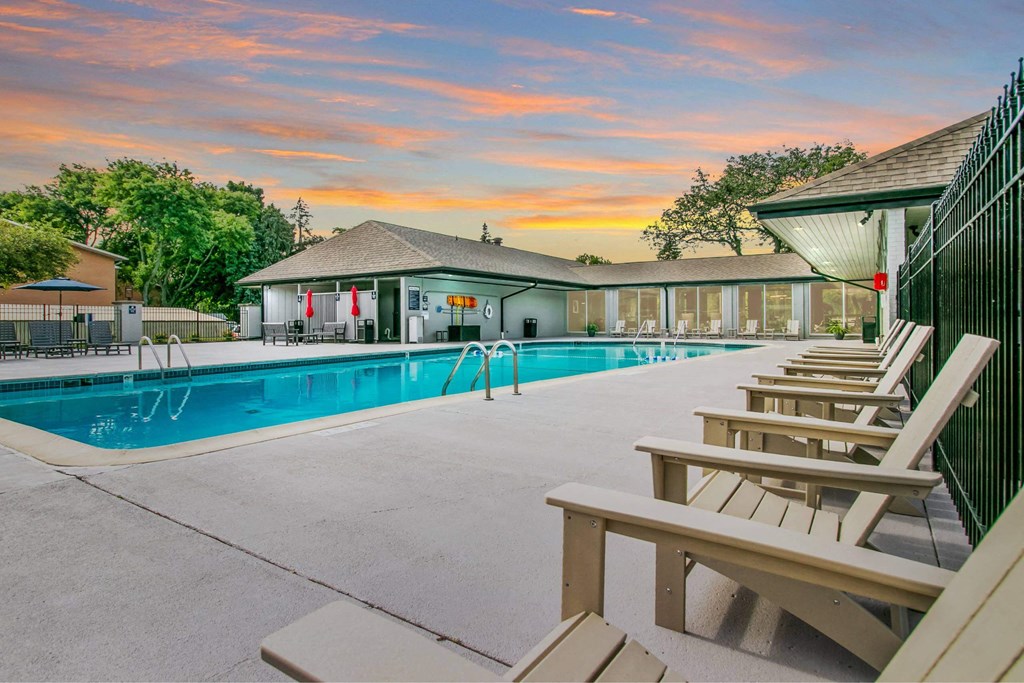 A poolside area with sun loungers and a building in the background at The Waverly on the Lake - Belleville, MI Apartment , Michigan