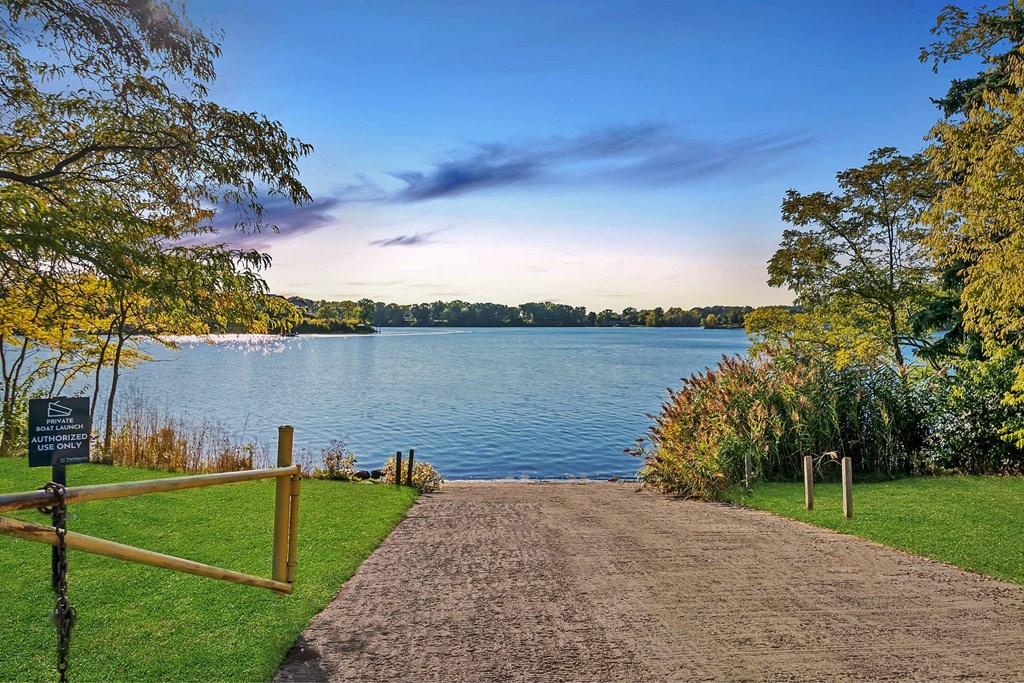 A pathway leads to a body of water with a sign on the left at The Waverly on the Lake - Belleville, MI Apartment , Michigan