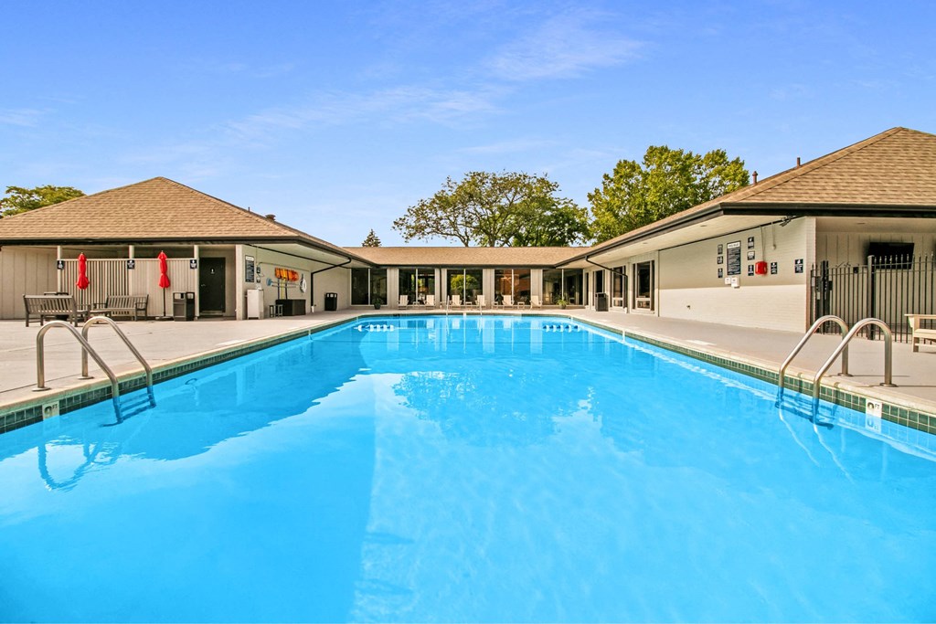 A large swimming pool in front of a building with a clear blue sky above at The Waverly on the Lake - Belleville, MI Apartment , Belleville, 95050