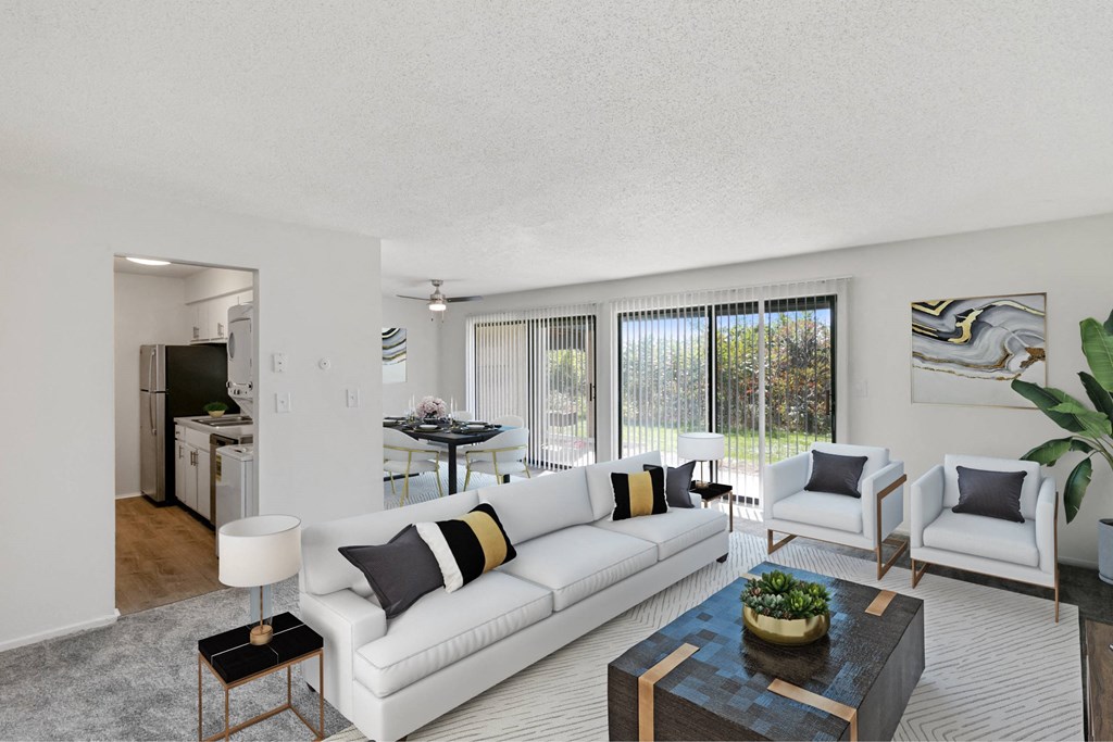A living room with a white couch, a coffee table, and a potted plant at The Waverly on the Lake - Belleville, MI Apartment, Belleville, MI, 95050