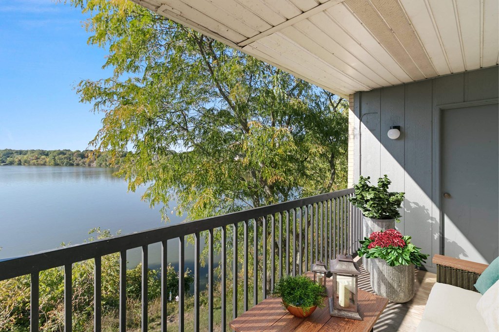 A balcony with a view of a lake and trees at The Waverly on the Lake - Belleville, MI Apartment , Belleville, 95050