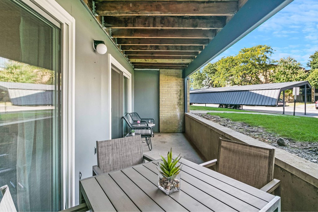 A wooden table with a potted plant on it sits on a patio at The Waverly on the Lake - Belleville, MI Apartment , Belleville, Michigan