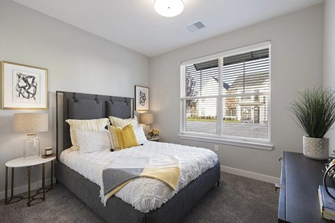 A bedroom with a large bed and a window with blinds.
