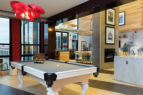 A pool table in a room with a fireplace and a fire burning.