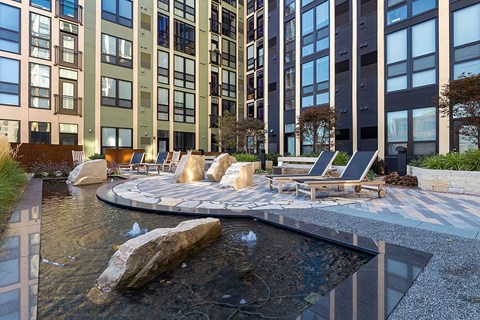 A modern outdoor seating area with a water feature in the foreground.