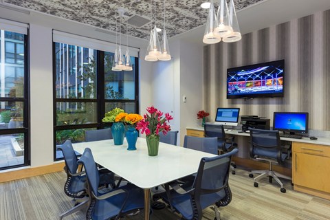 A conference room with a large table, chairs, and a television mounted on the wall.