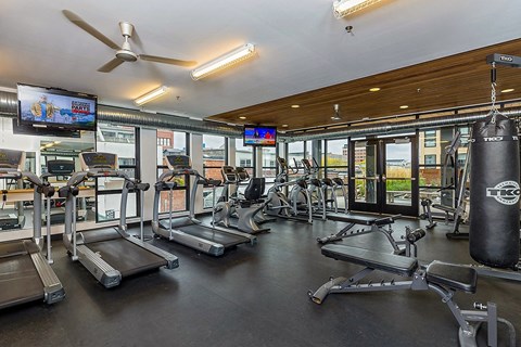 A gym with treadmills, a punching bag, and a television.