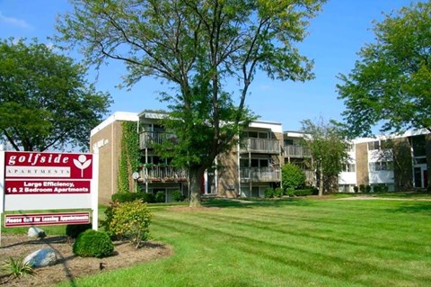 A sign for Golfside Apartments is in front of a building with a lawn in the foreground.