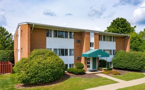 A building with a green awning and bushes in front.