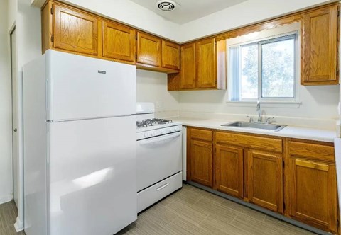 A white refrigerator is in a kitchen with wooden cabinets.