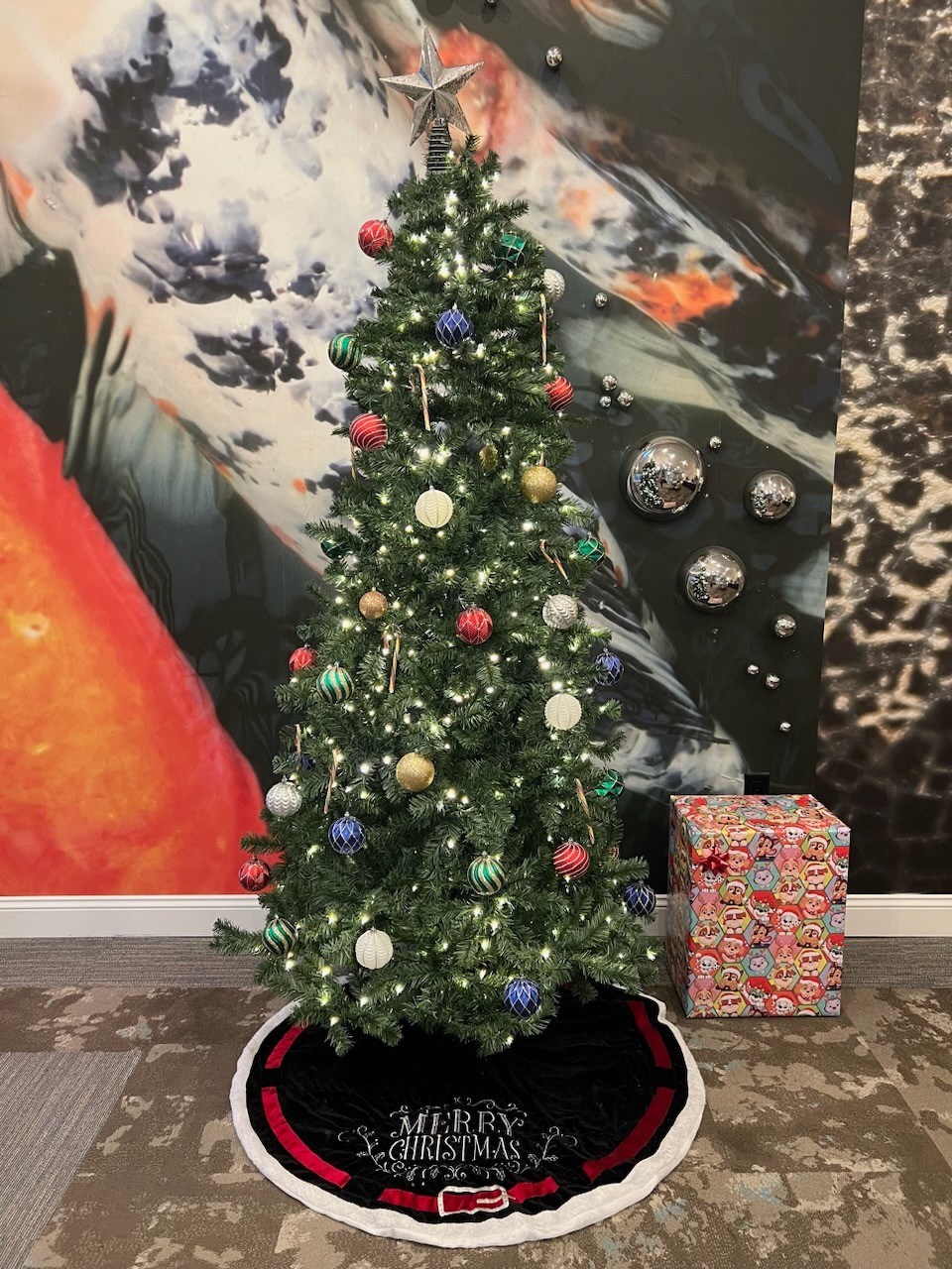 a christmas tree is in front of a painting