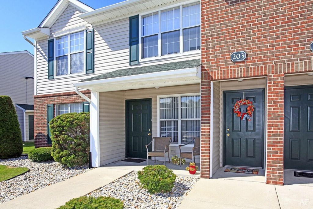 a home with two black doors and a red brick wall