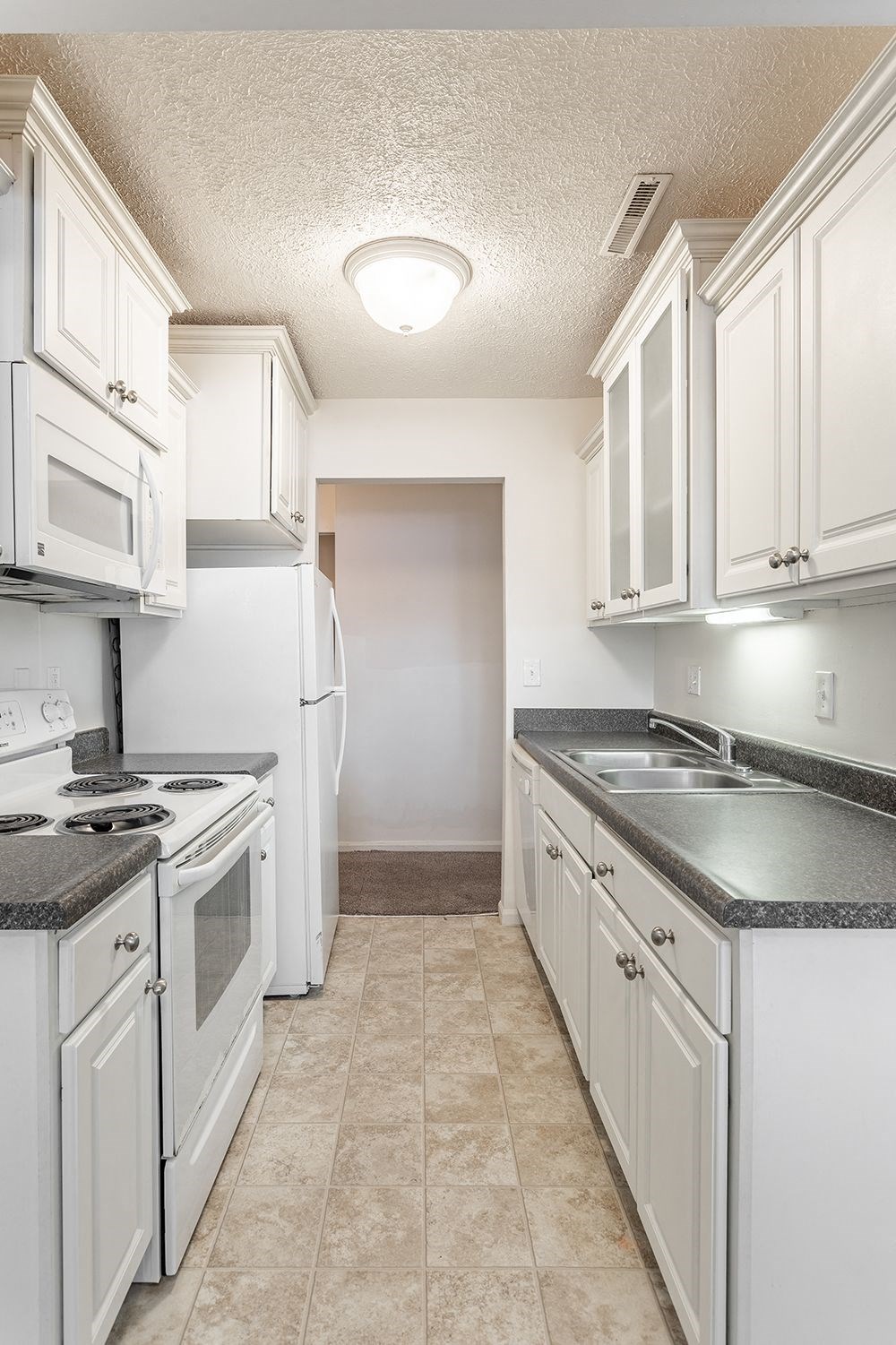 an empty kitchen with white cabinets and white appliances