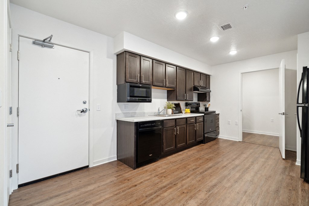 a kitchen with dark wood cabinets and white countertops and a refrigerator