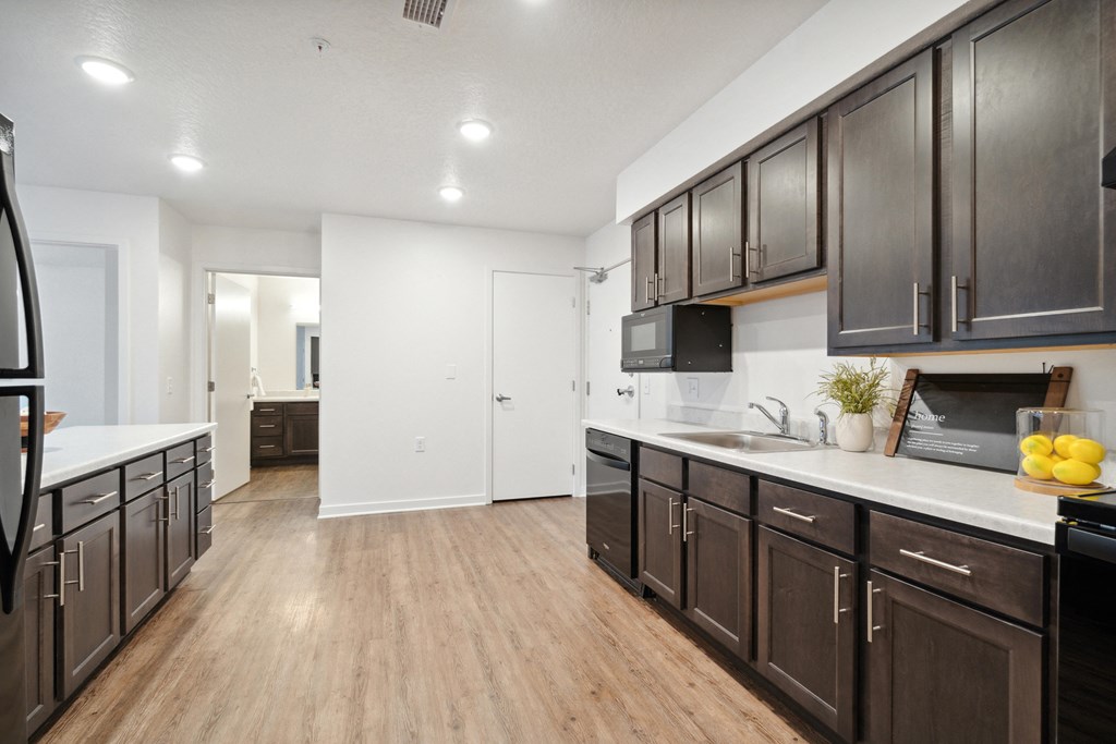 an open kitchen with dark wood cabinets and white countertops and a living room