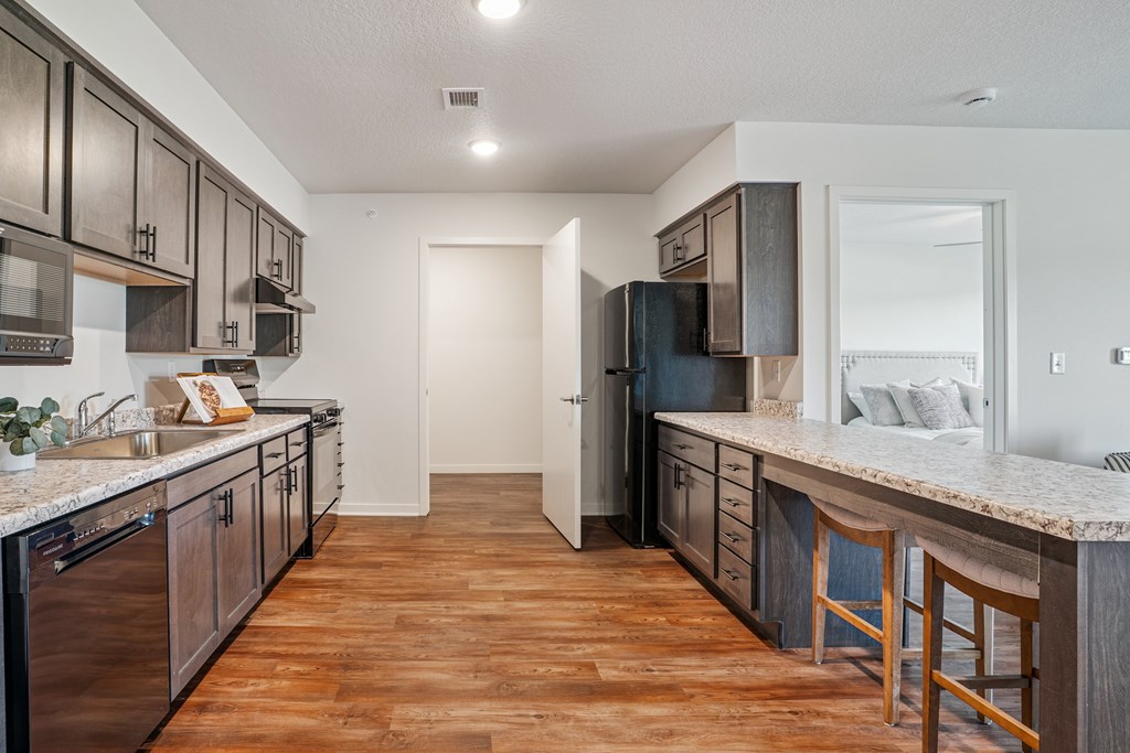 A kitchen with wooden floors and black appliances.