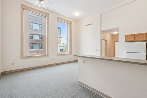 A spacious room with a large window and a ceiling fan.
