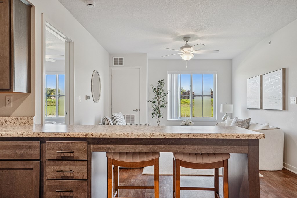 A kitchen with a marble countertop and wooden chairs.