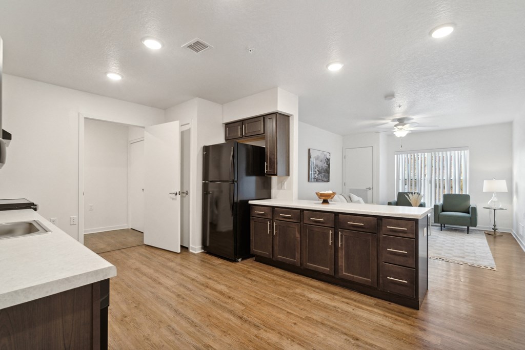 an open kitchen and living room with a refrigerator and a sink