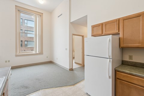 A white refrigerator sits in a kitchen with wooden cabinets.