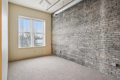 A room with a brick wall and a window with a view of trees.