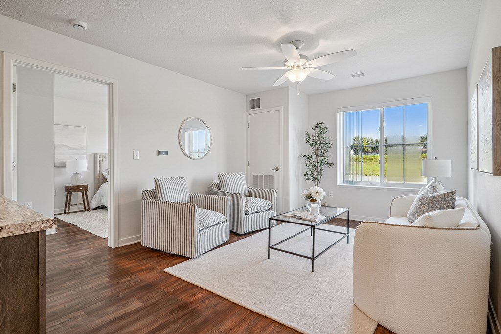 A living room with a striped chair and a round mirror on the wall.