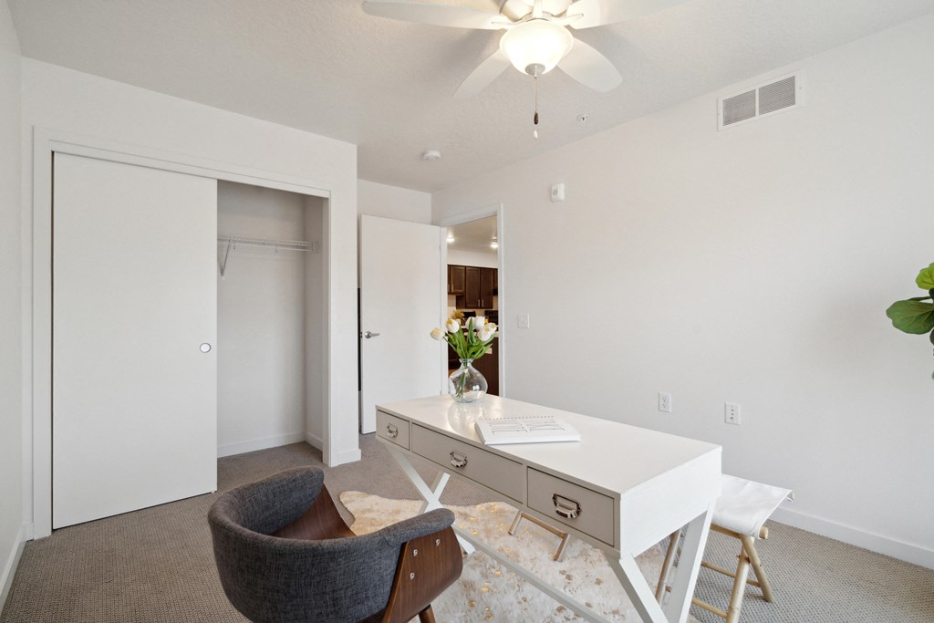 a living room with a white desk and chair and a closet