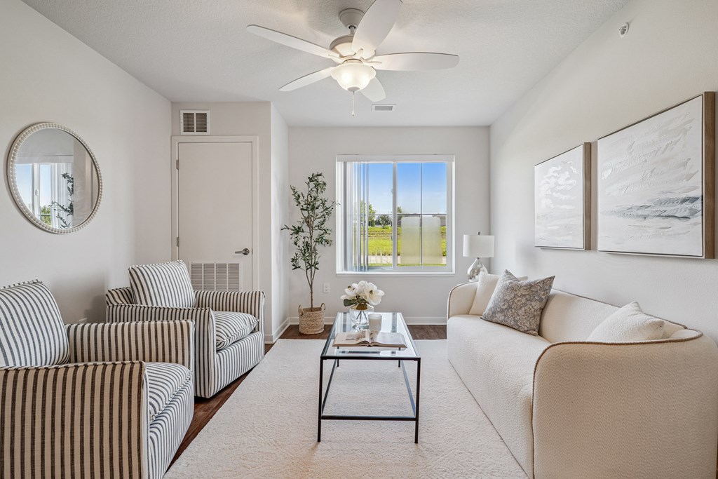 A living room with a striped couch, a coffee table, and a ceiling fan.