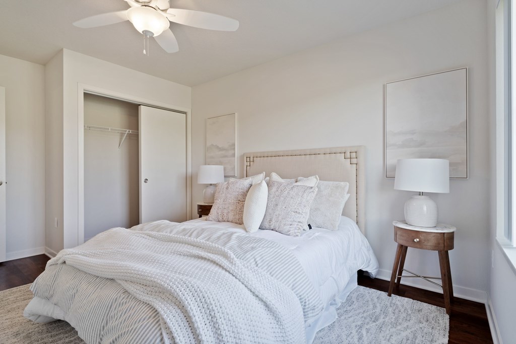 A bedroom with a bed, a ceiling fan, and a chair.