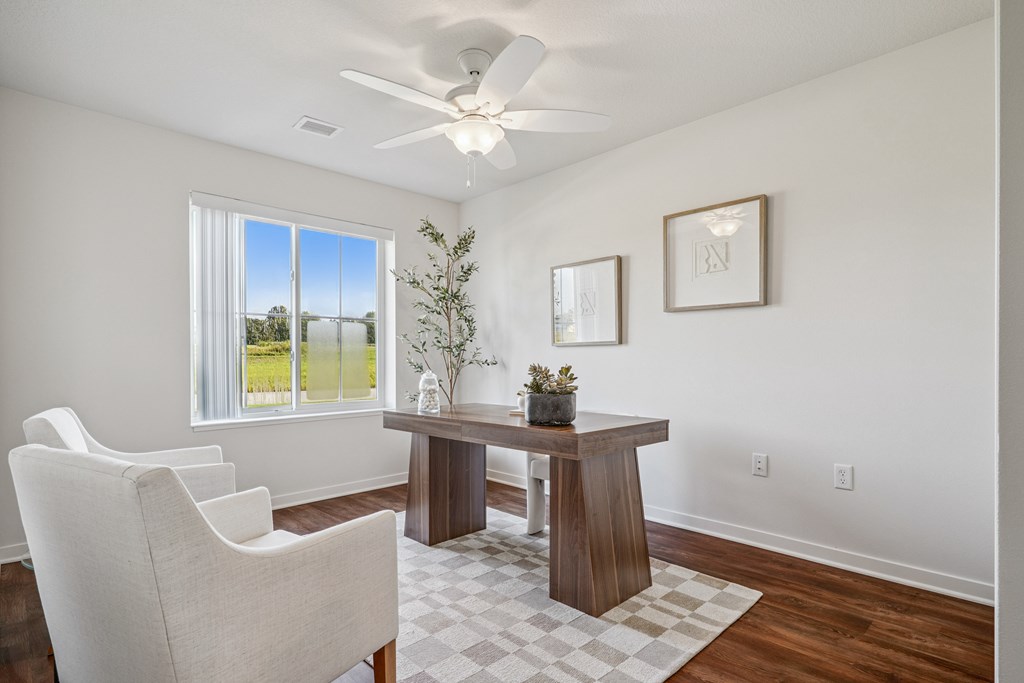 A room with a table, chairs and a ceiling fan.