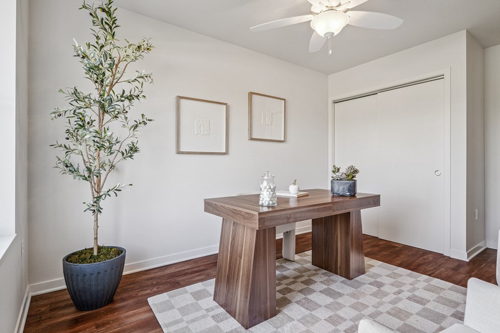 A room with a table, a plant, and two pictures on the wall.