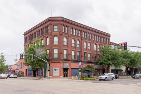 A large red brick building with a green awning sits at a street corner.
