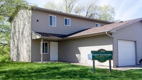 A house with a sign that says Prairie Townhomes in front of it.