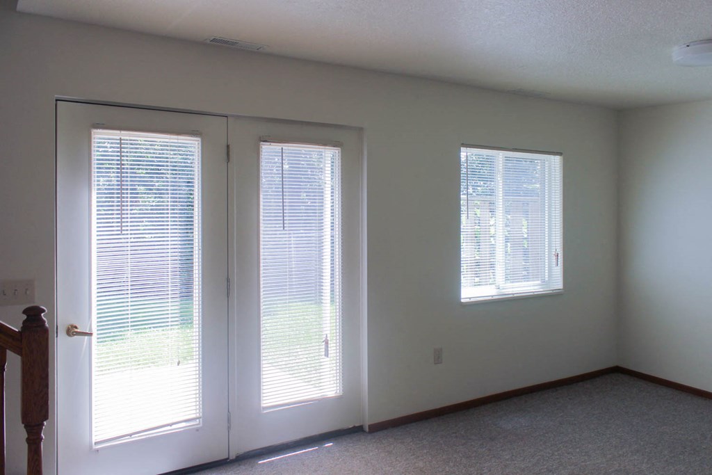 A room with a carpeted floor and a window with blinds.
