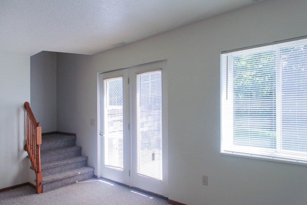 A room with a staircase and a window with blinds.