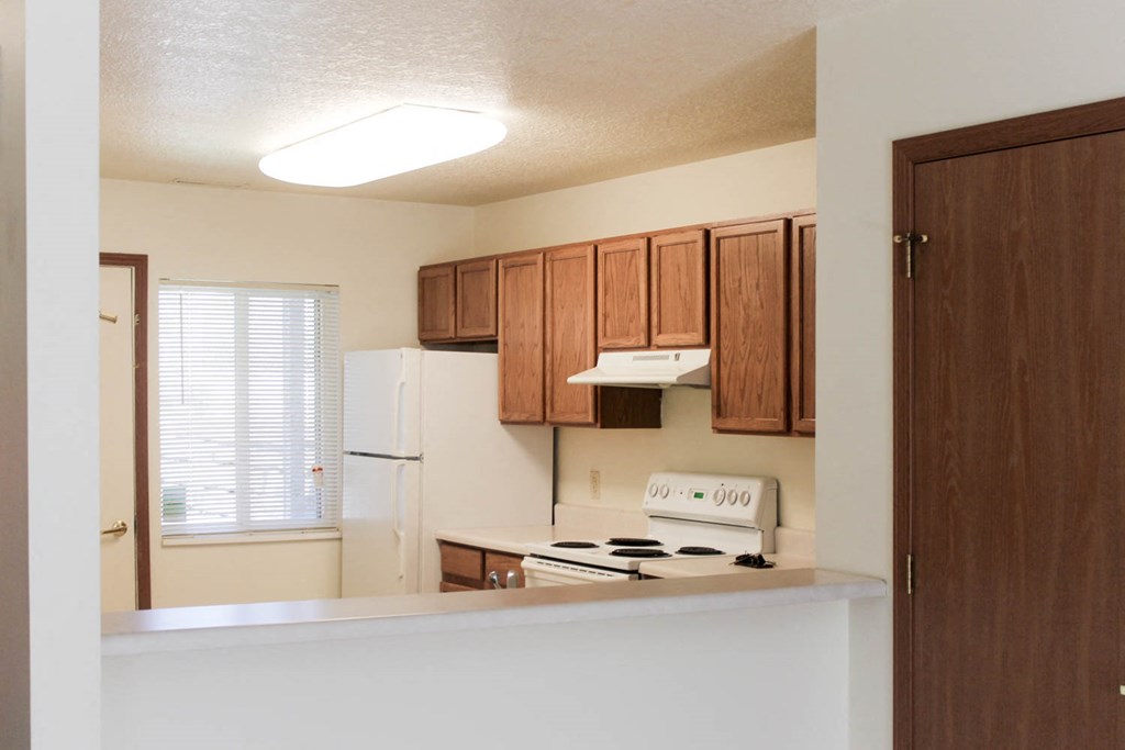 A kitchen with wooden cabinets and a white stove top oven.