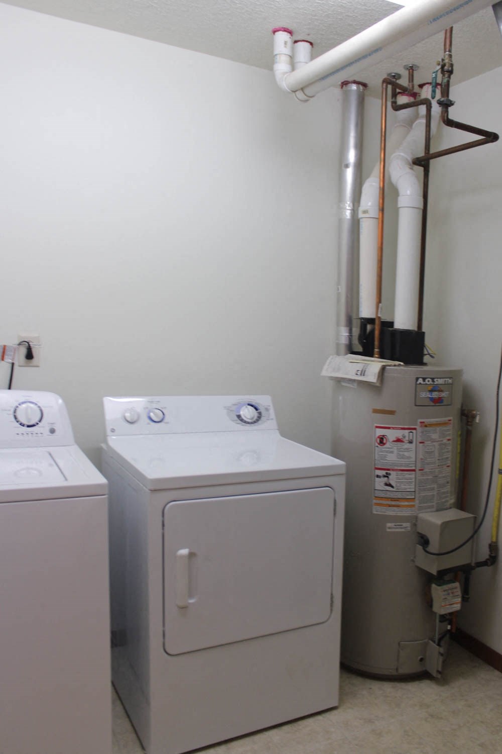 A wall-mounted washer and dryer are installed in a small room.