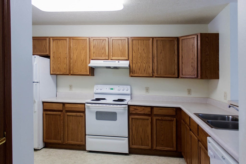 A kitchen with white appliances and wooden cabinets.