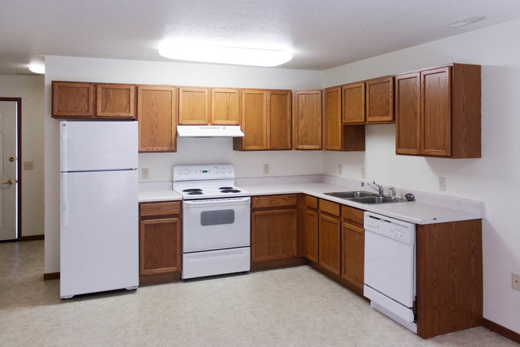 A kitchen with white appliances and wooden cabinets.