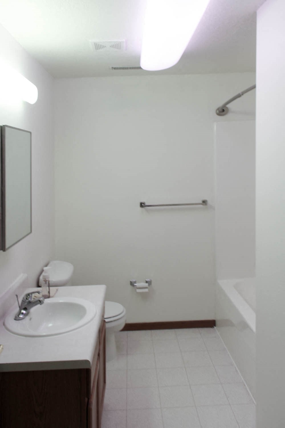 A white bathroom with a sink, toilet, and a shower.