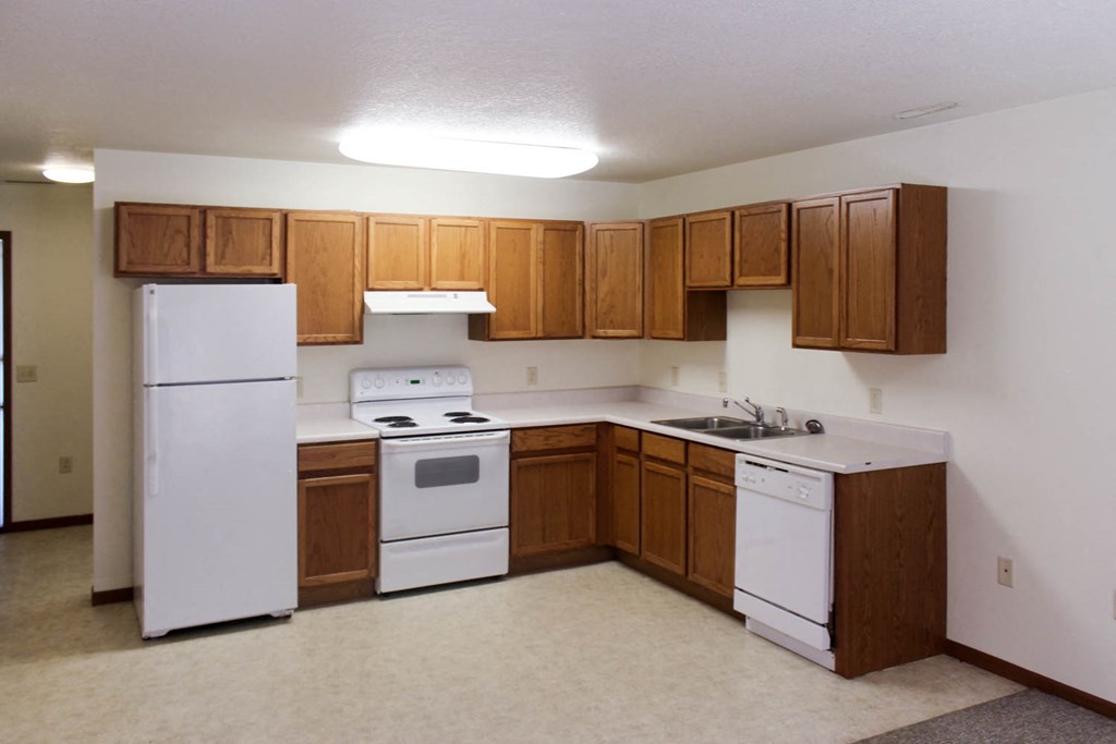 A kitchen with white appliances and wooden cabinets.