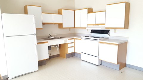 A white kitchen with wooden cabinets and appliances.