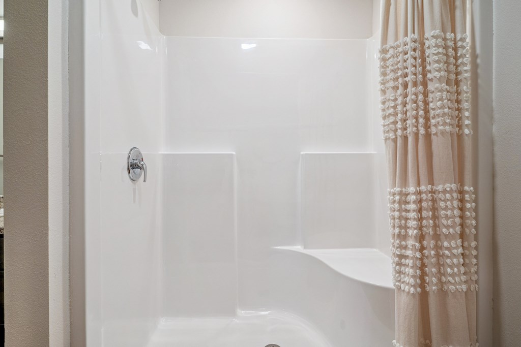A white bathroom with a shower and a shower curtain.