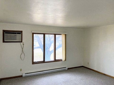 an empty living room with a window and a heater