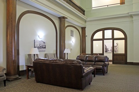 A living room with a brown couch and a lamp.